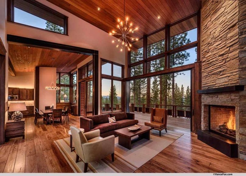 Mountain cabin great room with vaulted wood ceiling, stone fireplace, and forest views