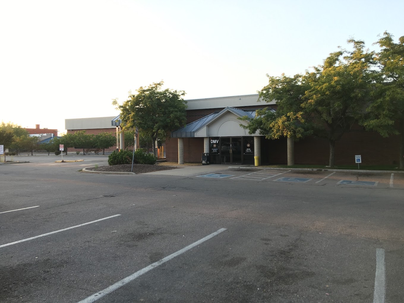Wide view of a brick DMV building with mature trees and parking lot