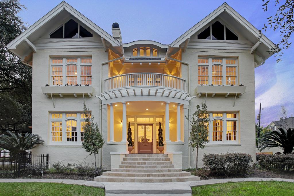 Historic Craftsman home with deep eaves, columned porch, and warm interior lighting