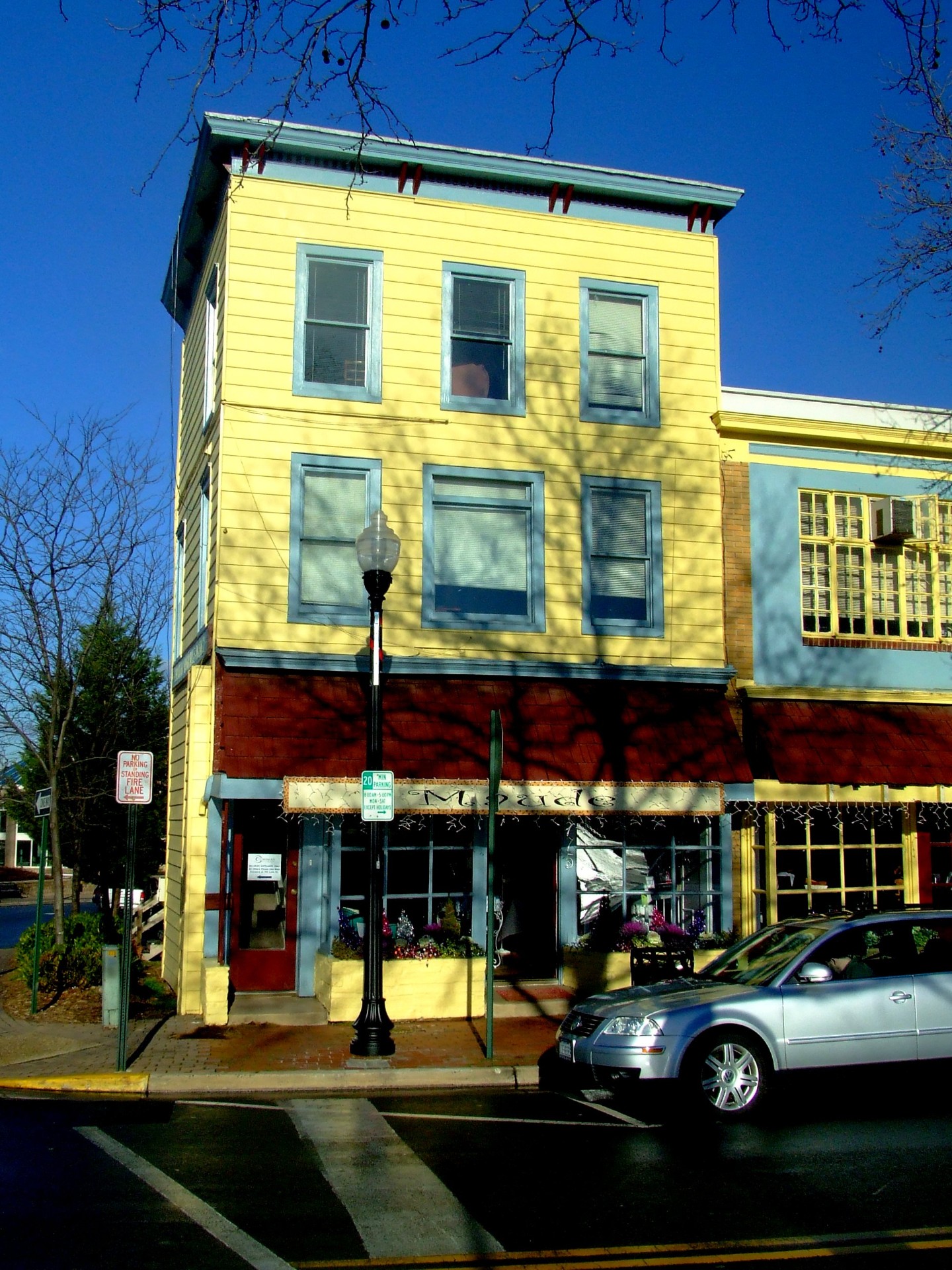 Three-story yellow clapboard mixed-use building on a main street corner