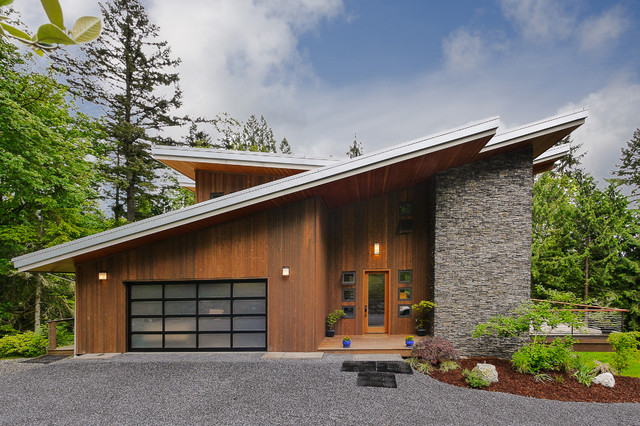 Modern wood-clad home with dramatic sloped metal roof and stone chimney