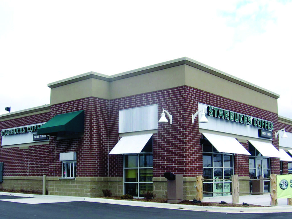 Brick coffee shop with drive-thru and awnings on a corner lot